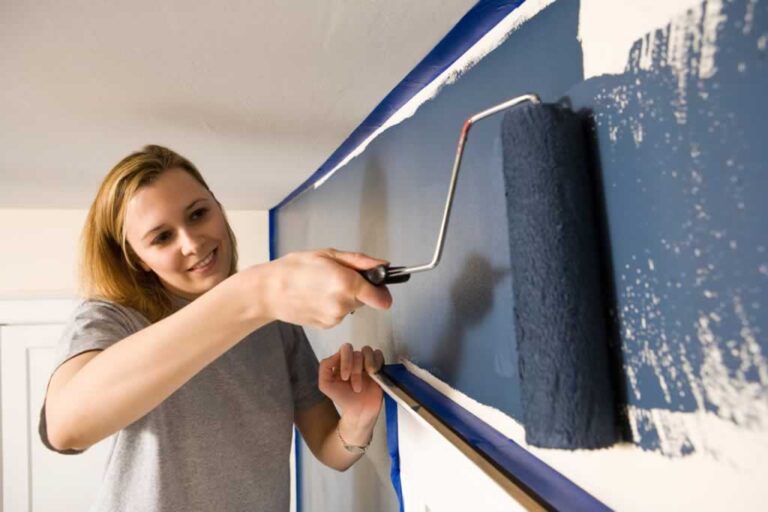 girl painting wall with paint roller