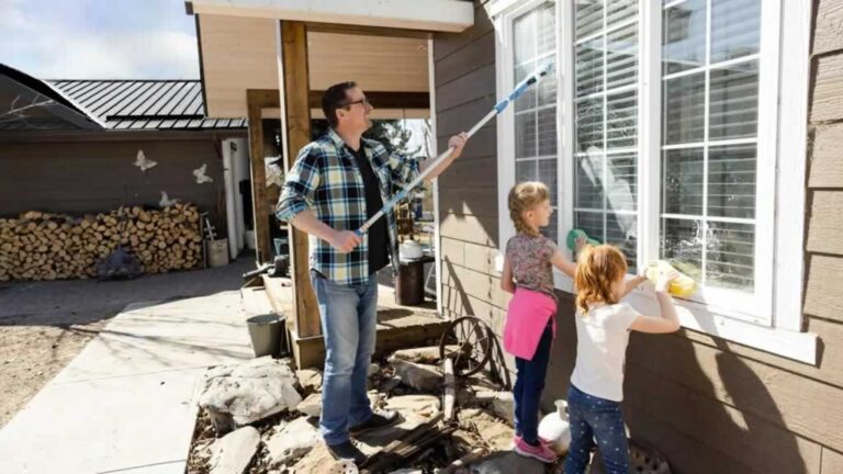 father with kids washing windows from the outside