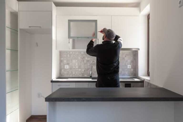 man mounting new kitchen cabinets in remodeled kitchen
