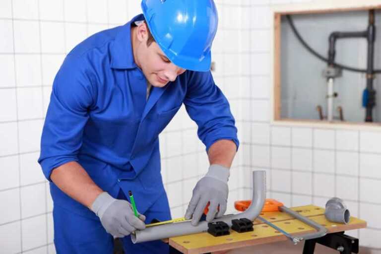 plumber measuring drain pipe for cutting