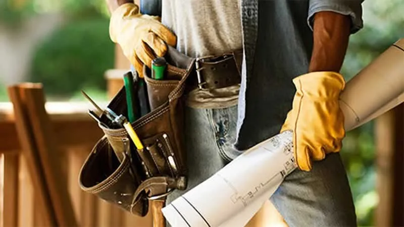 handyman with tool belt and renovation plans