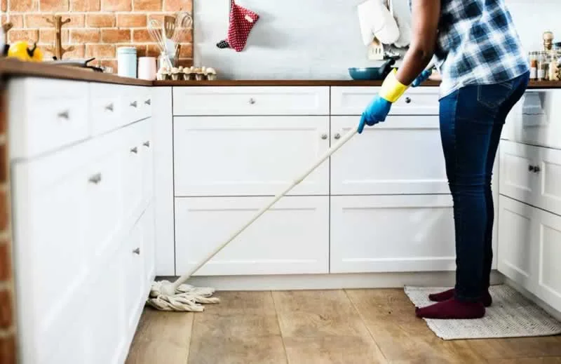 women cleaning kitchen floor with a mop
