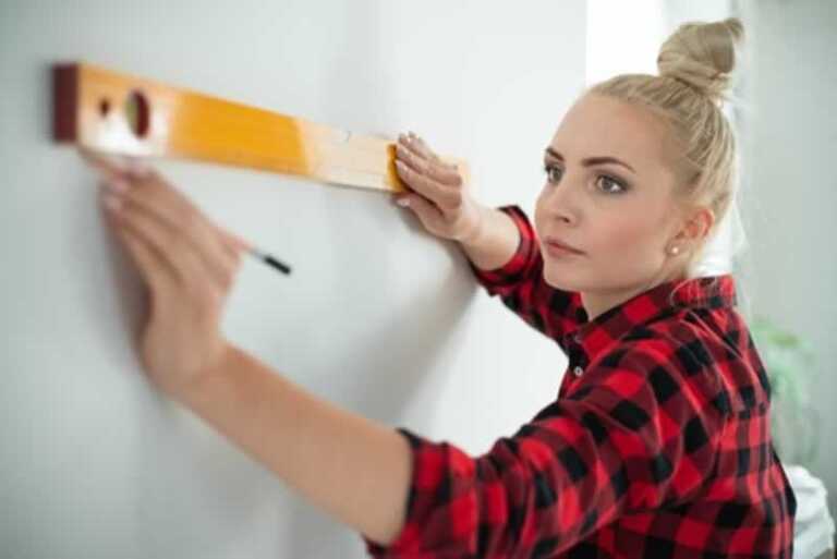 women measuring holes on the wall with level
