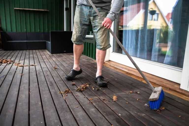 man sweeping wooden patio
