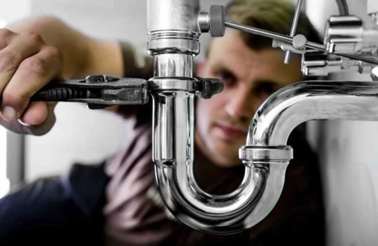 man fixing the drain pipe under the sink
