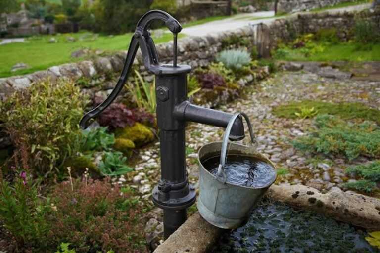 manual water well pump with bucket of water