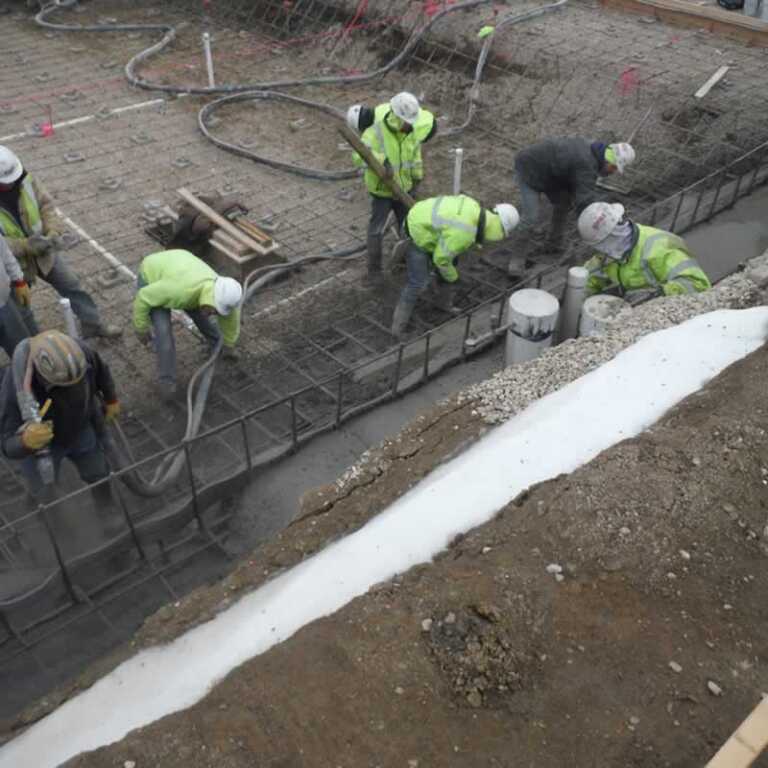construction workers pouring shotcrete in the foundations
