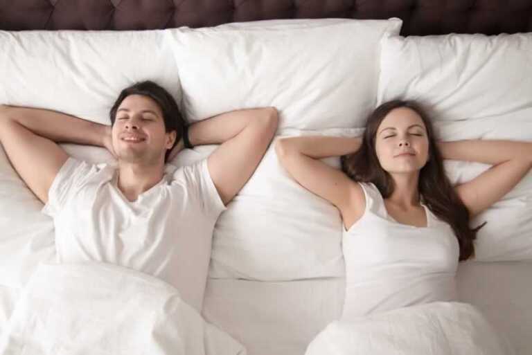 couple sleeping in a bed full of pillows