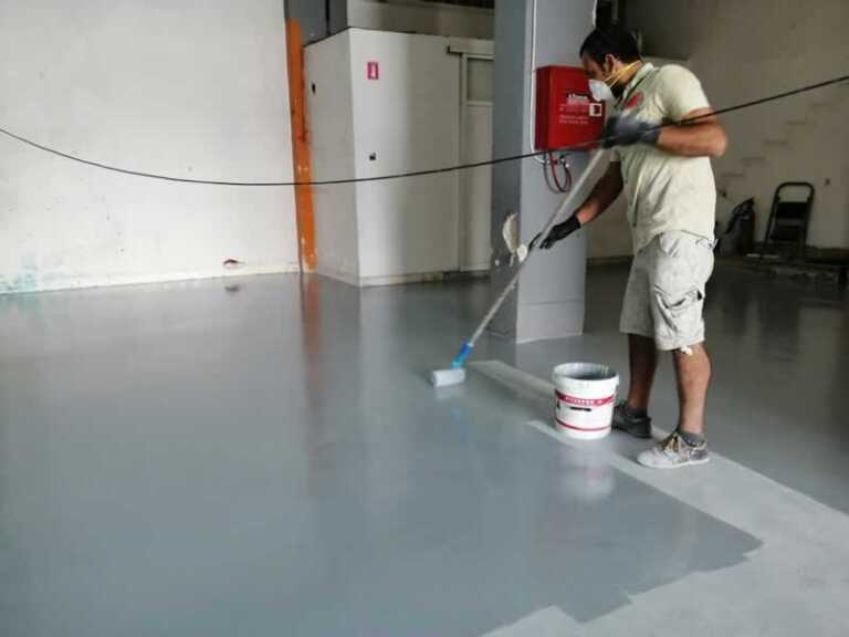 man laying epoxy floor in the basement
