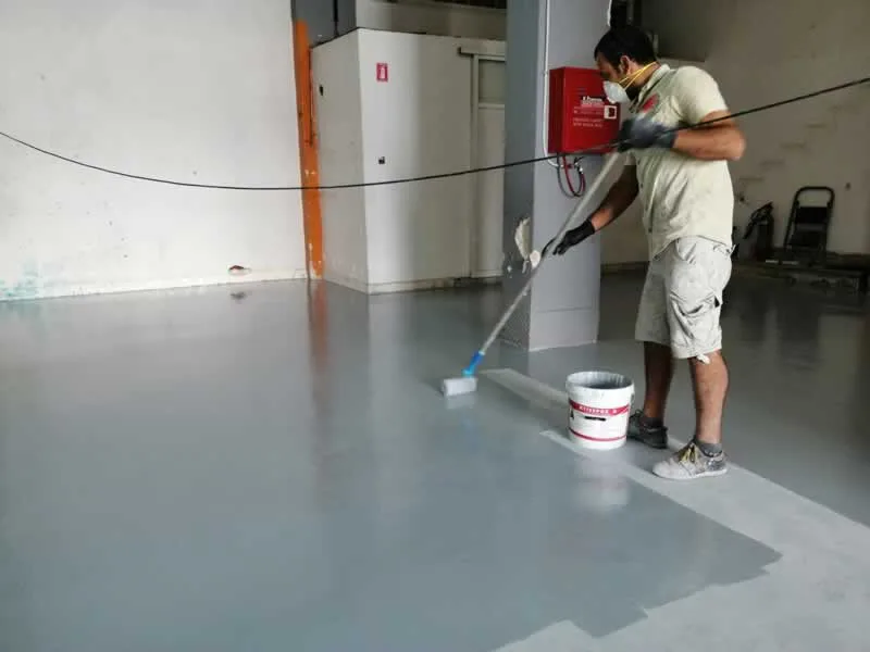 man laying epoxy floor in the basement