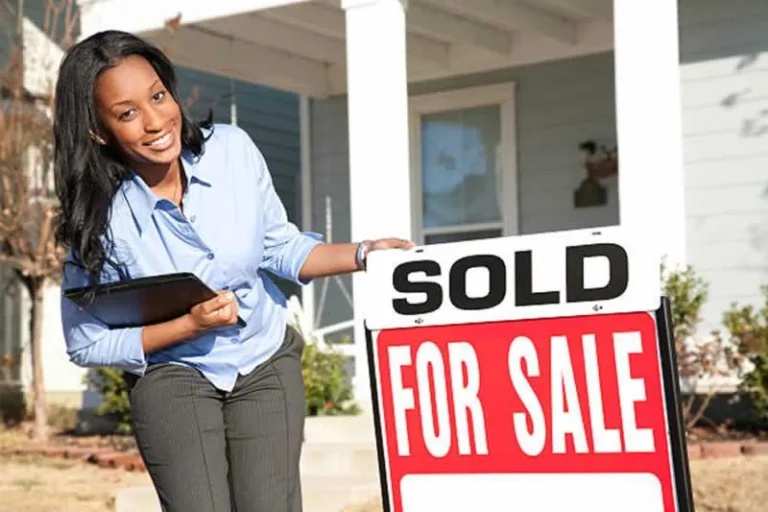 real estate agent putting a sold sign in front of the house