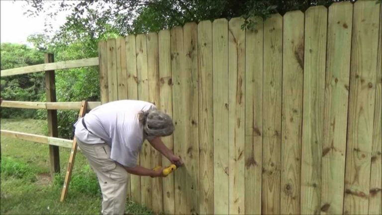 man attaching planks to privacy fence