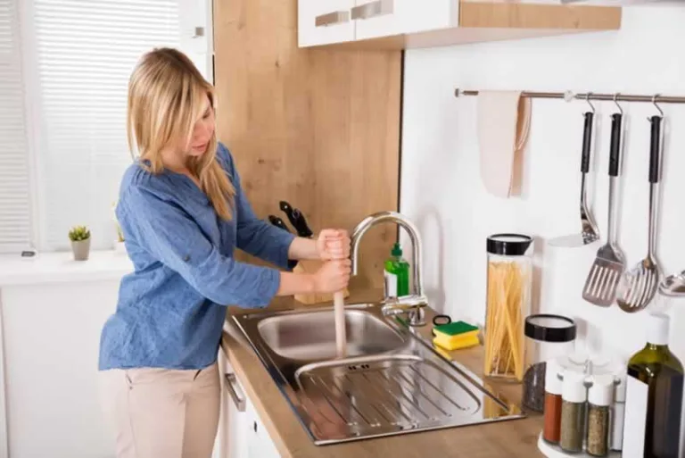 unclogging the drain with a plunger