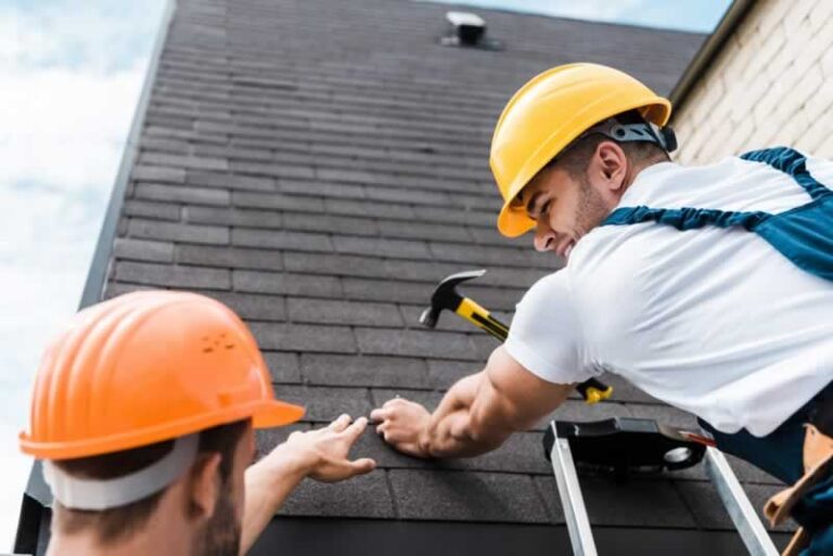 roofers fixing shingles on the roof