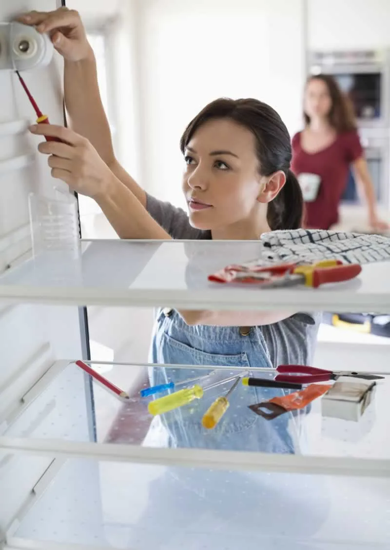 woman fixing the light inside the refrigerator
