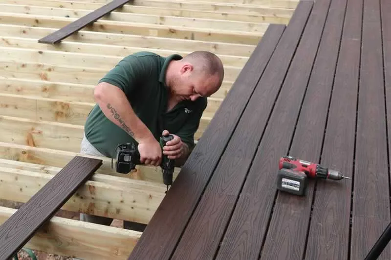 man installing wooden planks on deck