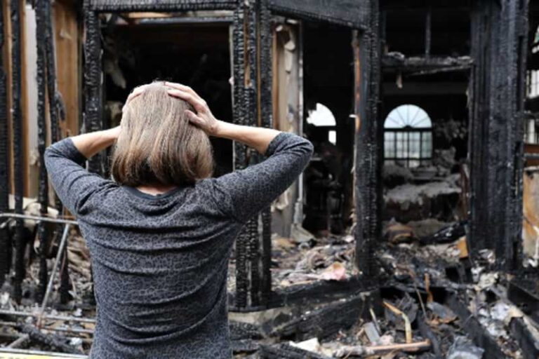 women in front of burned house