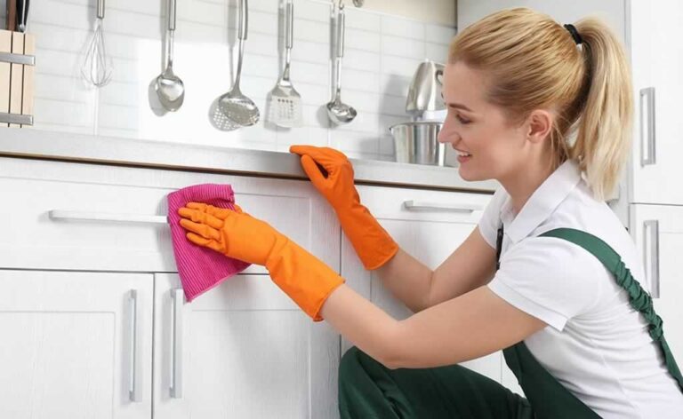 woman dusting kitchen cabinets