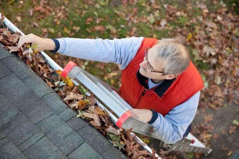 man cleaning gutters from the ladders
