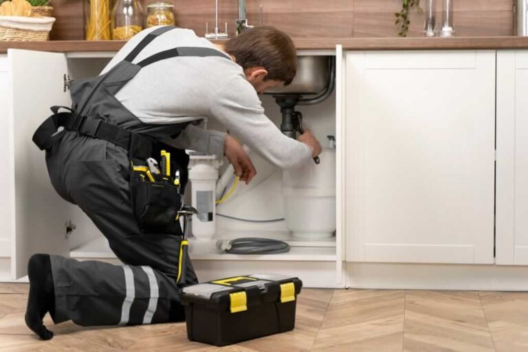 plumber fixing sink drain in the kitchen