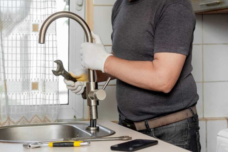 plumber changing faucet in the kitchen