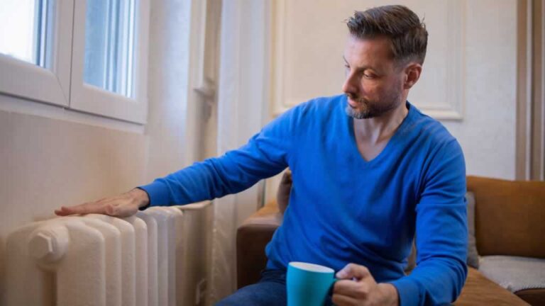 man drinking tea and checking the radiator