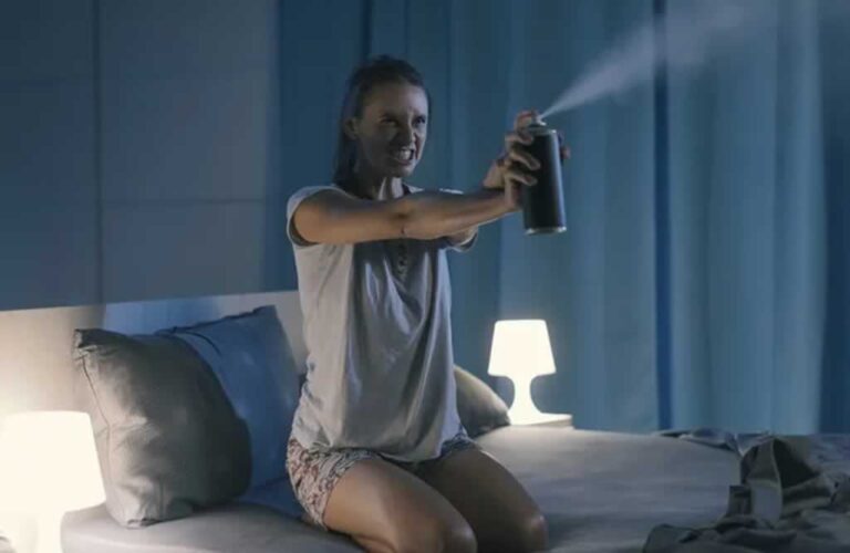woman on bed spraying pests
