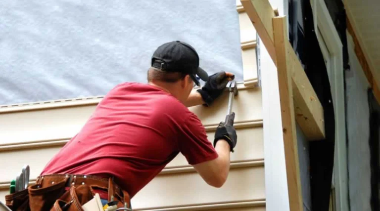 contractor fixing damaged siding on house