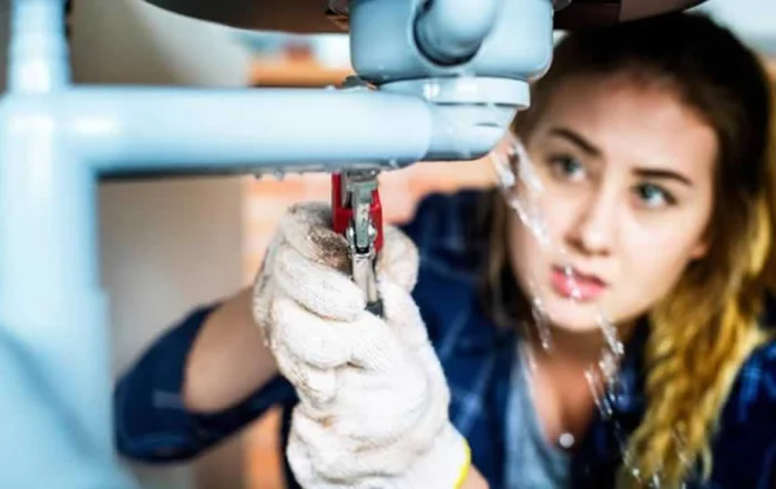 woman fixing the drain underneath the sink