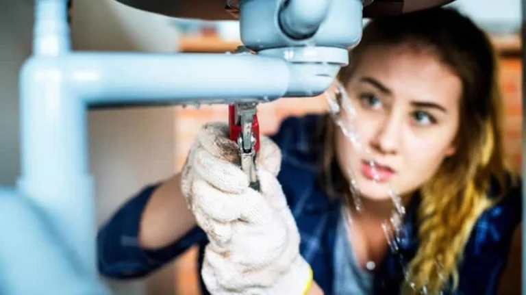 woman fixing the drain underneath the sink