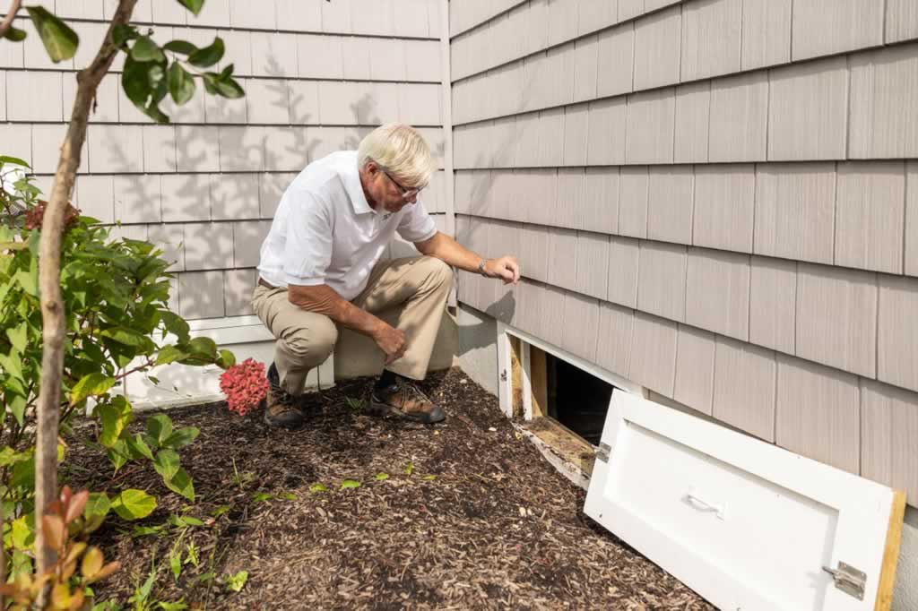 man checking crawl space under family house