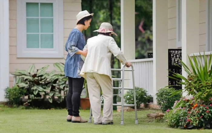 assistant helping a senior into the house