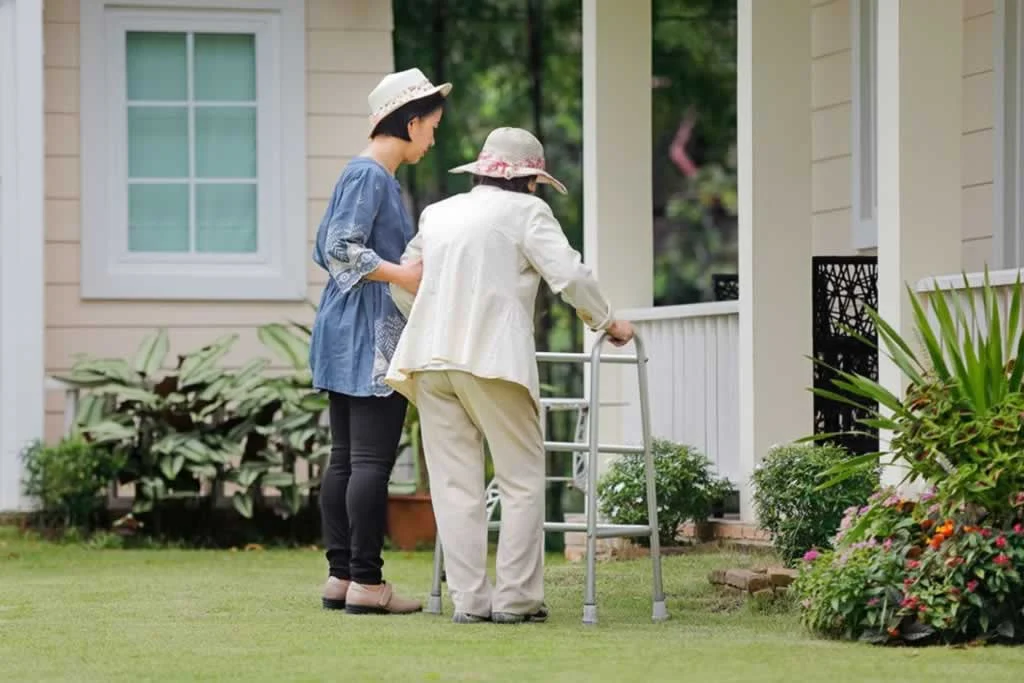 assistant helping a senior into the house