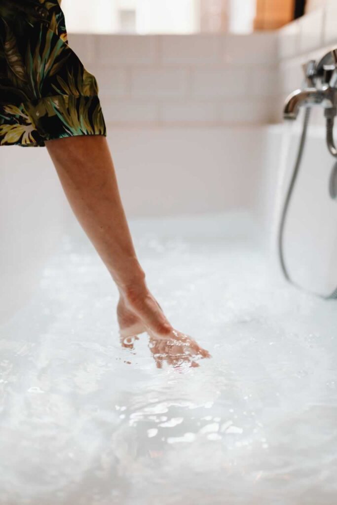 person testing water temperature in walk in bathtub