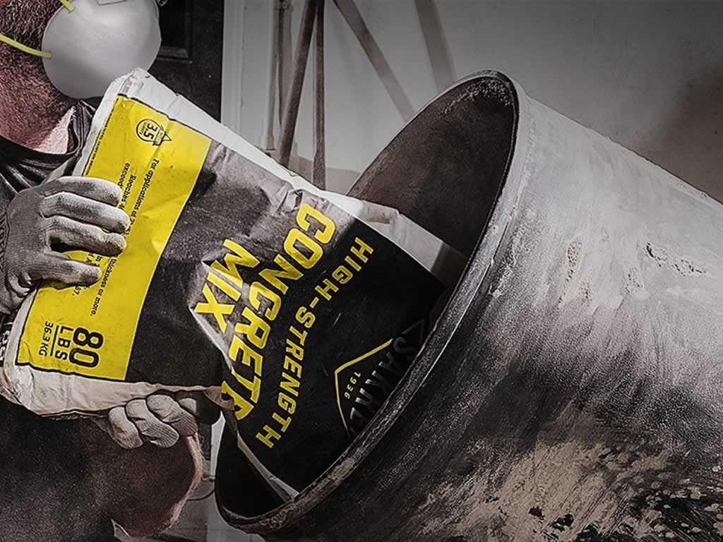 pouring a bag of bagged concrete mix into a cement mixer