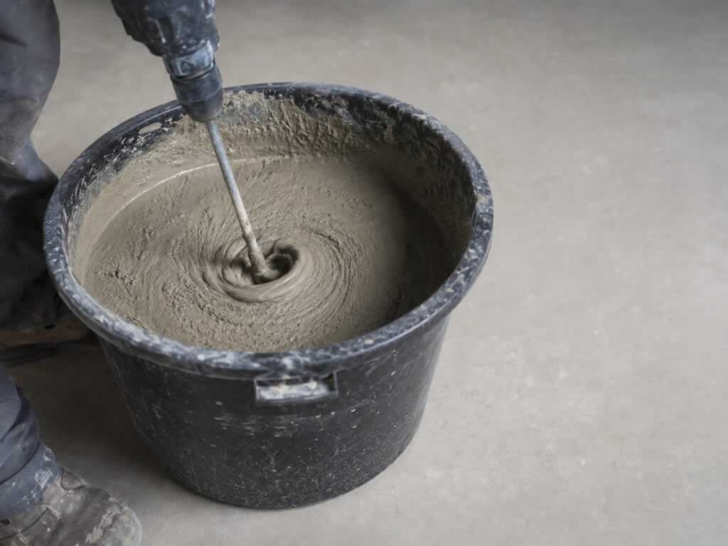 mixing homemade cement with a mixer in the bucket